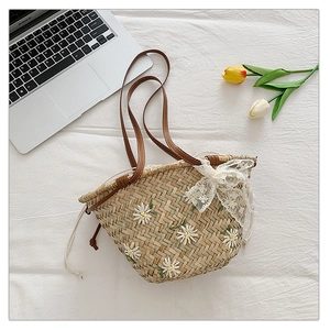 Detail of straw woven tote bag with white daisy embroidery and lace bow decoration