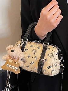 Klassische beige Boston Bag mit Bärendruck und Plüschtier-Anhänger von Model gehalten