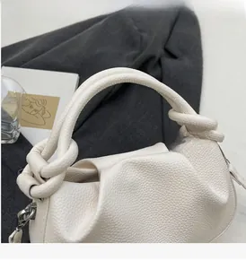 Close-up of white lychee leather texture and stylish knot handle on cloud bag