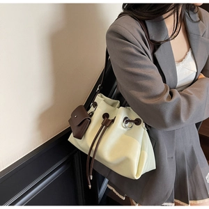 Detail of light green pleated bucket bag with mini pouch and brown drawstring closure
