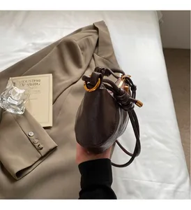 Close-up of dark brown leather handbag with luxury gold hardware and knot handle detail