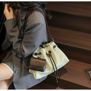 Close-up of light green pleated bucket bag with brown drawstrings and matching mini pouch