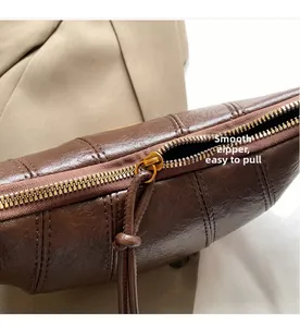 Detail of dark brown leather bag with smooth gold zipper and vertical grain texture