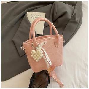 Dettaglio borsa a secchiello rosa plissettata con ciondolo a cuore di perle e pizzo bianco