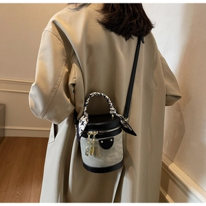 Detail of grey canvas bucket bag with silk scarf handle and golden lock charms