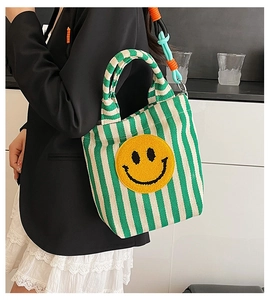 Détail du sac cabas en toile à rayures vertes avec smiley brodé et bandoulière tissée