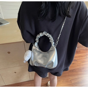 Detail of silver pleated handbag with metal chain strap and white plush doll charm