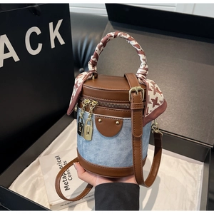 Detail of a denim bucket bag with brown leather trim and houndstooth silk scarf handle