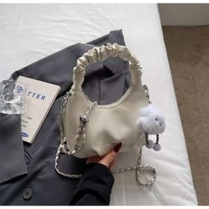 Detail of off-white pleated cloud bag with silver chain strap on a grey blazer