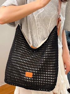 Large black woven mesh tote bag with adjustable brown leather strap and brand patch