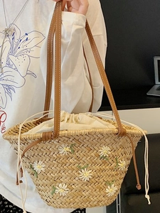 Handwoven straw tote bag with daisy embroidery and brown leather straps for summer beach