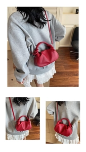 Detail of red cloud handbag with soft pleated design and adjustable leather strap on model