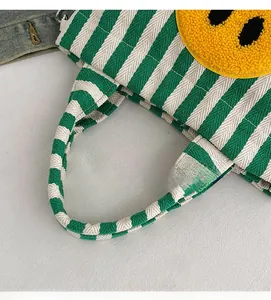 Détail du sac cabas en toile à rayures vertes et blanches avec broderie smiley jaune