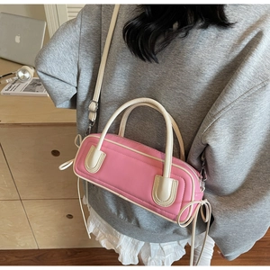 Detail view of pink and white cylinder bag with bow accents and adjustable strap