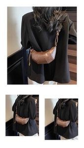 Detail of a brown croissant shoulder bag featuring pleated faux leather and adjustable strap
