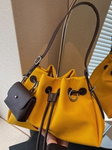Chic yellow pleated bucket bag with brown strap and mini coin purse in a modern style