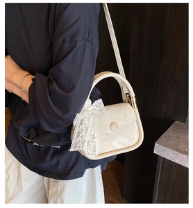 Détail du sac à main crème avec un grand nœud en dentelle et des boucles en métal doré