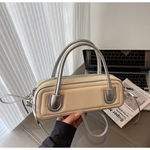 Detail of a chic beige handbag with silver trim next to a laptop in a lifestyle setting
