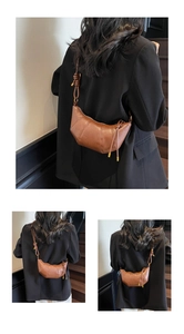 Close-up of brown croissant shoulder bag with lychee texture and knotted strap detail