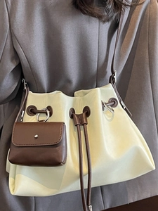Minimalist light green pleated bucket bag with brown strap shown on model's shoulder