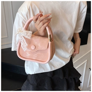 Détail d'un sac à main en cuir verni rose avec un nœud en dentelle blanche élégant