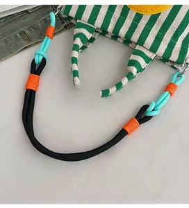Détail d'un sac en toile rayé avec bandoulière en corde multicolore et anneau en métal