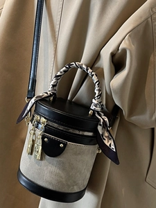 Chic grey bucket bag with black leather trim and decorative silk scarf on handle