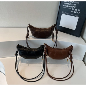Detailed view of three minimalist pleated croissant bags in black, coffee, and tan colors