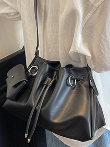 Minimalist black pleated bucket bag with drawstring closure and matching small coin purse