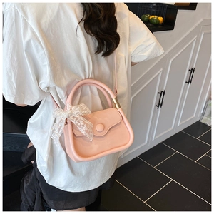 Vue détaillée du sac à main carré rose orné d'un nœud en dentelle blanche sur l'anse