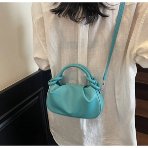 Close-up of bright blue pleated cloud bag with pebbled leather texture and crossbody strap