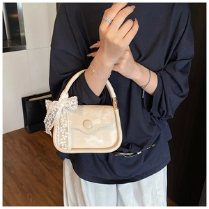 Détail d'un petit sac à main carré blanc crème avec un nœud en dentelle élégant et fermoir