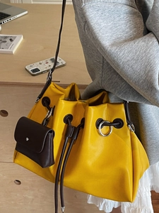Bright yellow pleated bucket bag with brown accents and large silver metal rings
