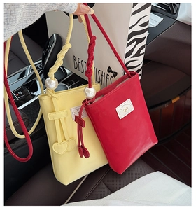 Close-up of PU leather mini phone bags with pearl handles and heart charms in a car interior