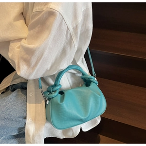 Detail of teal leather cloud bag featuring pleated design and round top handle accessory