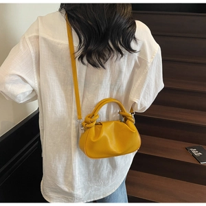 Close-up of bright yellow cloud bag with lychee grain leather and knotted handle detail