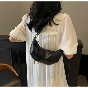 Detail of black crescent shoulder bag with pleated texture and gold metal accents