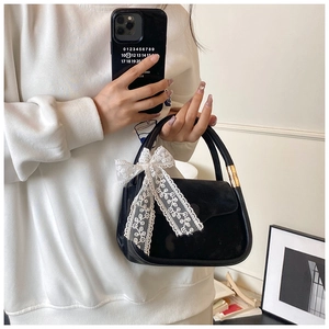 Détail du sac à main en velours noir avec nœud en dentelle blanche et boucle dorée
