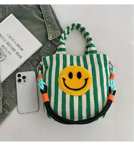 Détail du sac en toile à rayures avec écusson smiley jaune et bandoulière en corde