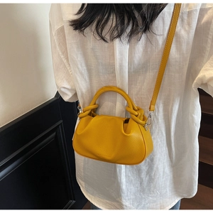 Detail of yellow lychee grain leather cloud bag with knotted handle on a model