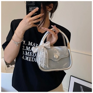 Détail d'un sac à main argenté métallisé avec nœud en dentelle et poignée ronde