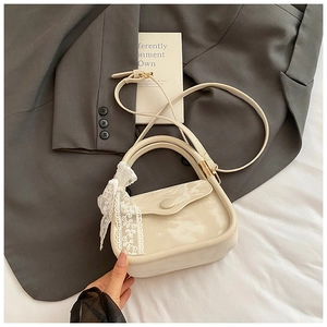 Détail d'un sac à main carré chic avec un nœud en dentelle blanche et bandoulière réglable