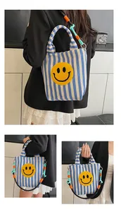 Détail du sac fourre-tout en toile à rayures bleues avec écusson smiley jaune