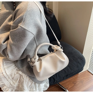Chic white lychee leather cloud bag with knotted handle shown in a daily lifestyle setting