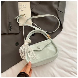 Détail du sac à main en cuir verni vert menthe avec nœud élégant en dentelle blanche