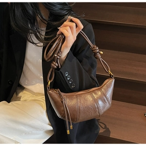 Detail view of a dark brown crescent croissant bag with vintage oil wax leather texture