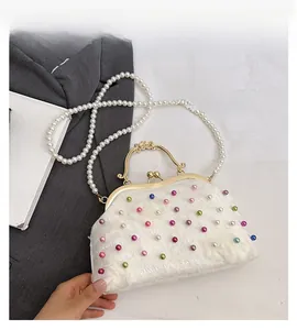Dettaglio della borsa a conchiglia bianca con perle colorate, fiori e manico di perle