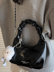 Minimalist black glossy pleated cloud bag with silver chain strap and plush pendant