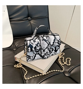 Detail of snake skin print handbag with top handle and gold beaded metal chain strap