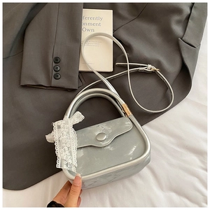 Détail du petit sac carré argenté avec un nœud en dentelle blanche et cuir brillant
